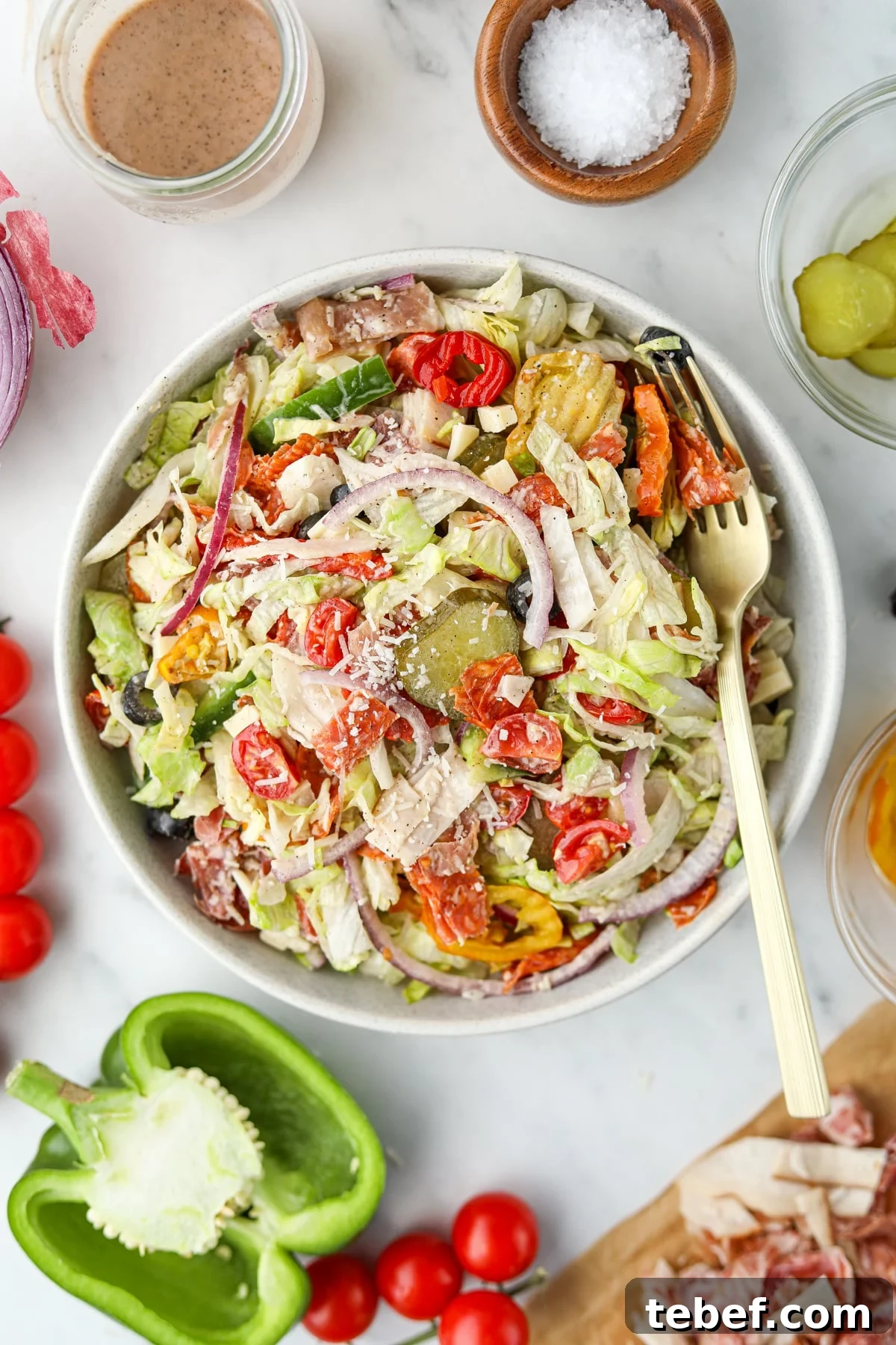 Italian Sub Sandwich Salad: Classic Deli Salad with Salami, Provolone & Italian Dressing 2 An bowl of salad topped with pickles, red onion, and parmesan cheese.