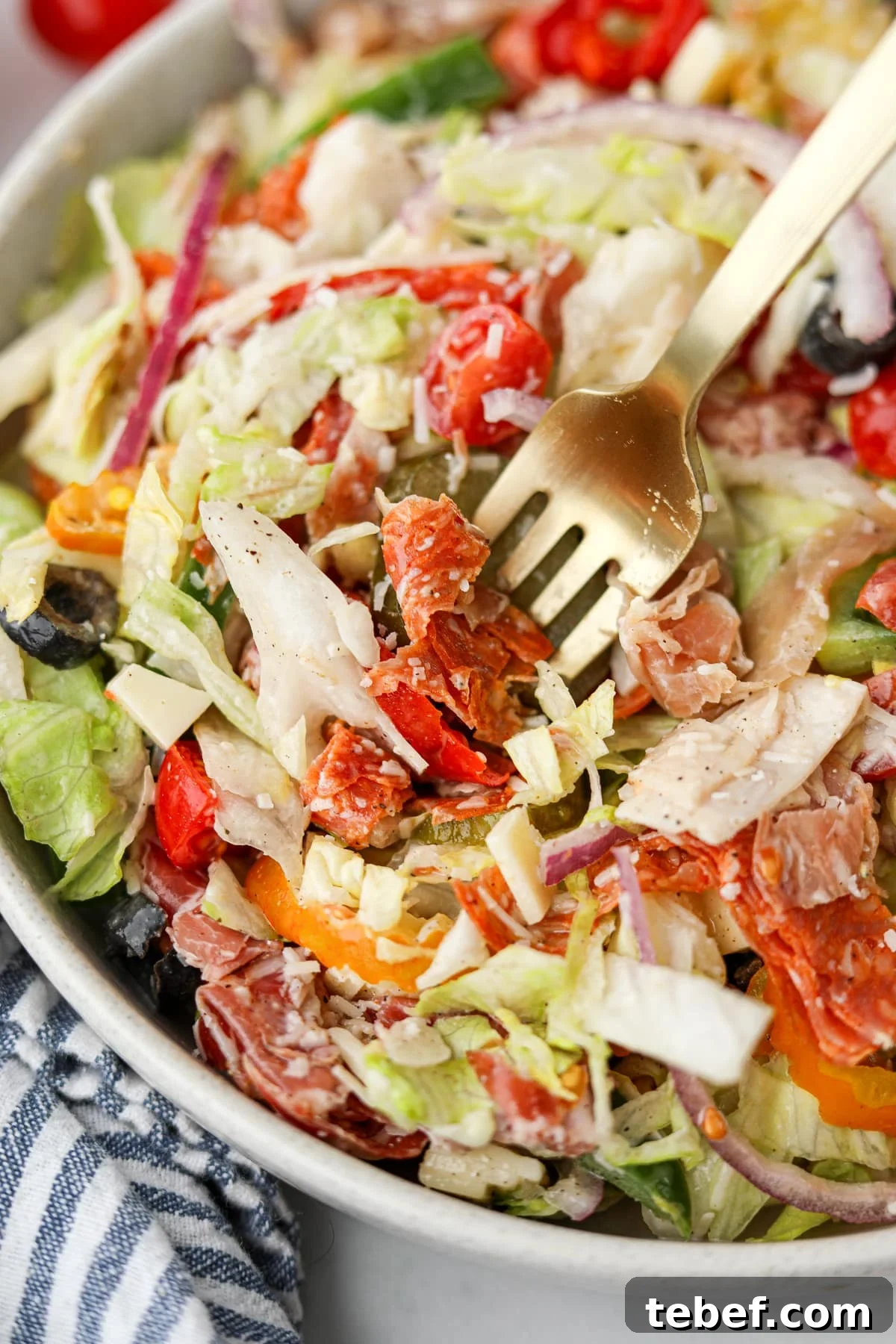 Italian Sub Sandwich Salad: Classic Deli Salad with Salami, Provolone & Italian Dressing 6 A fork taking a portion of salad from a bowl.