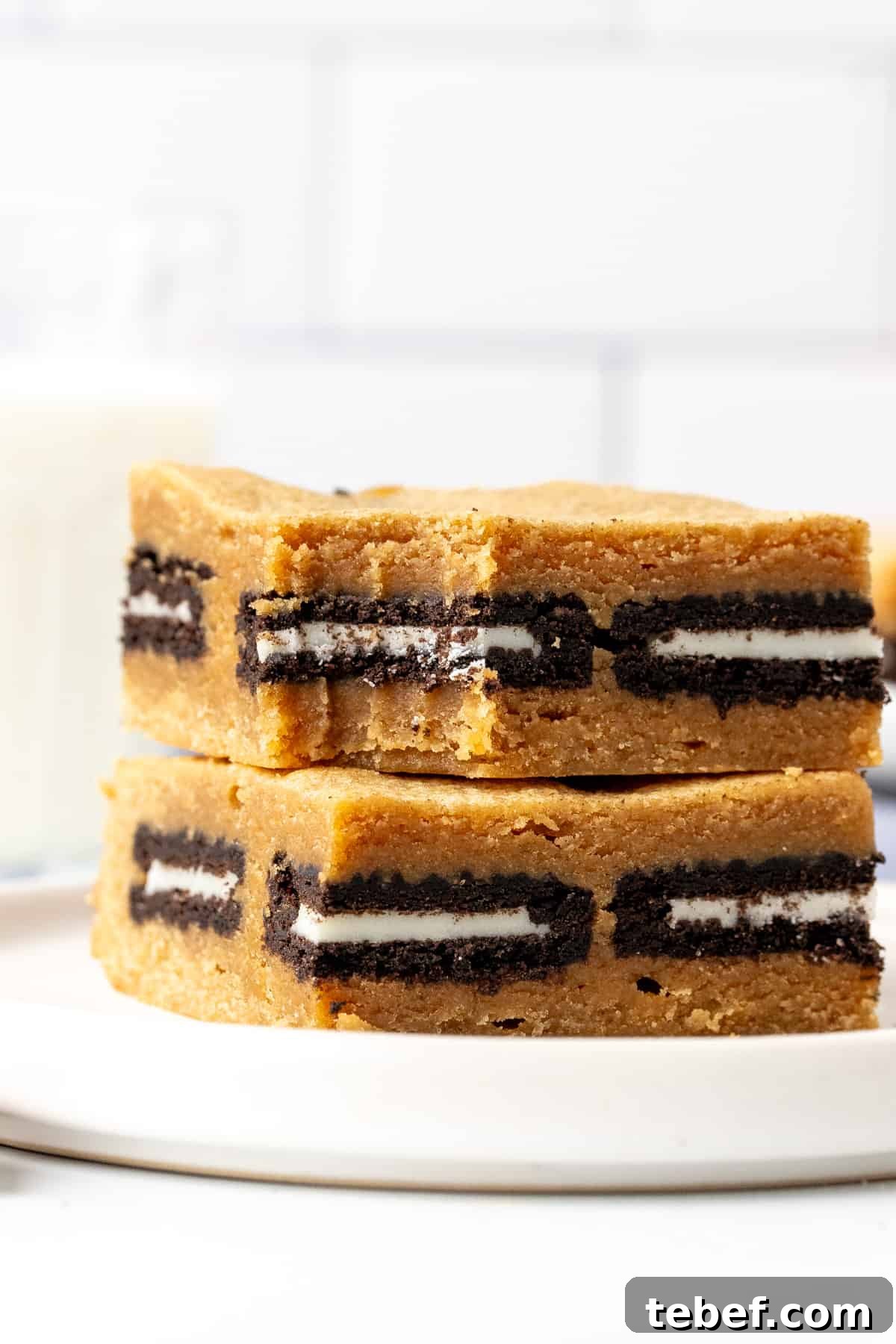 Peanut Butter Oreo Blondies Recipe — Gooey Cookie Bar Dessert 6 Two peanut butter Oreo blondies, one on top of each other on a plate.