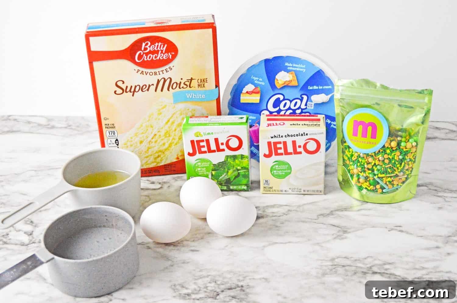 Ingredients needed to make lime jello poke cake including cake mix, whipped topping, eggs, and jello.
