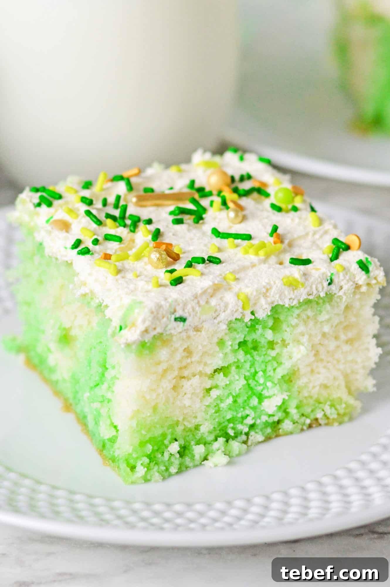 Close up shot of lime jello poke cake slice on a white plate.