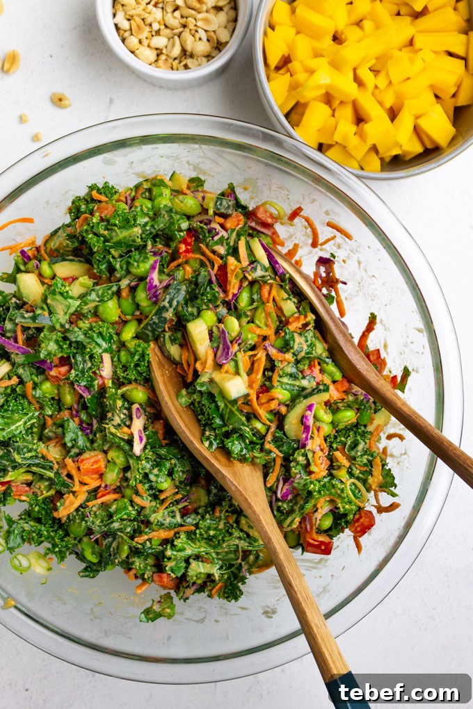 Thai Kale Salad with Creamy Peanut Dressing 9 Salad all mixed up in a mixing bowl with two wooden salad tongs.
