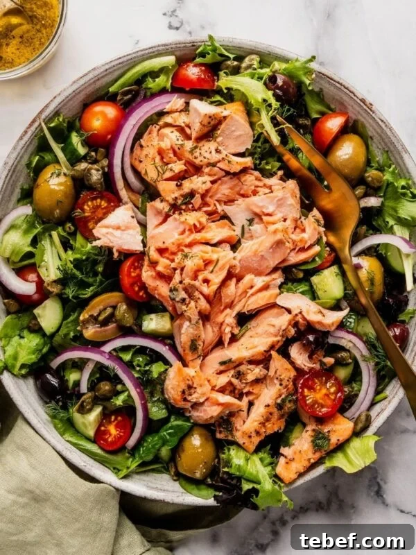 Mediterranean Salmon Salad bowl with flaky salmon over a bed of greens, tomatoes, olives and cucumbers.