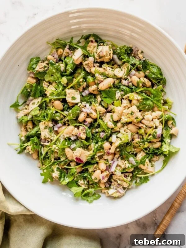 Bowl of tuna and white bean salad on a marble countertop.