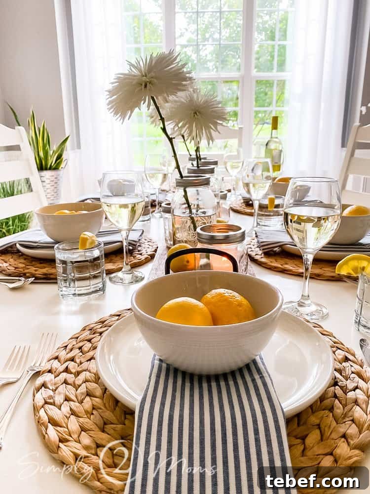 Chic Summer Dinner Party Ideas to Impress Your Guests 9 flowers in mason jars in middle of summer tablescape looking down table from end with placesetting and two lemons in bowl