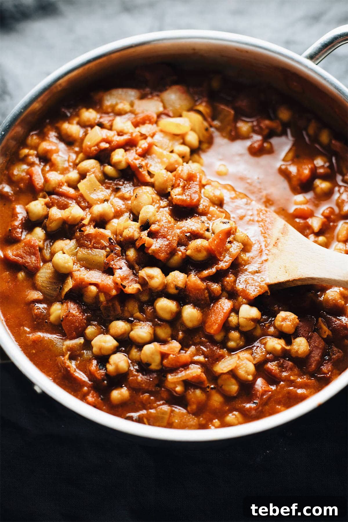 a pan of moroccan chickpea stew with a wooden spoon in it.