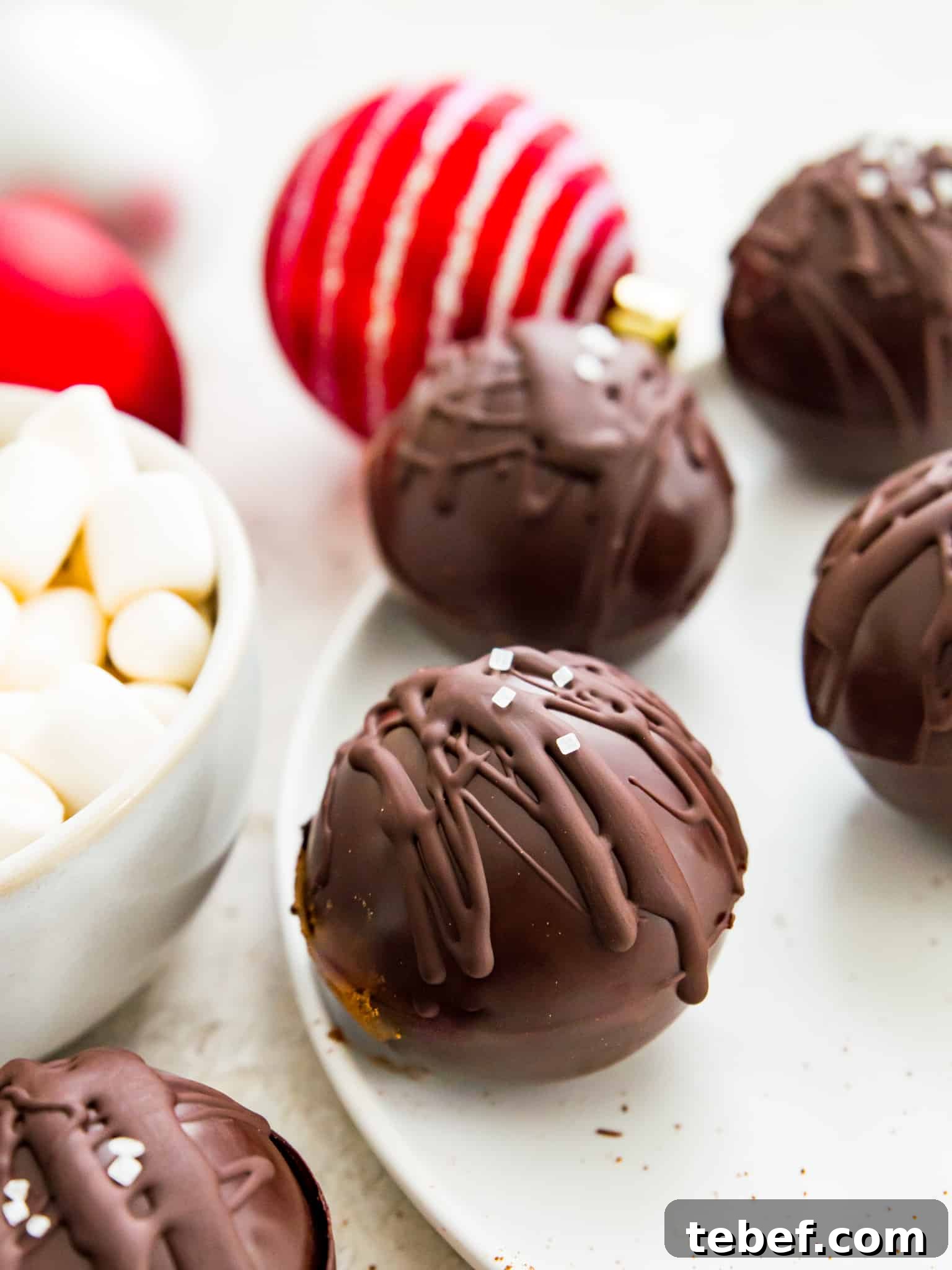 Vegan Hot Chocolate Bombs Hot chocolate bombs on a plate with a bowl of marshmallows beside them.