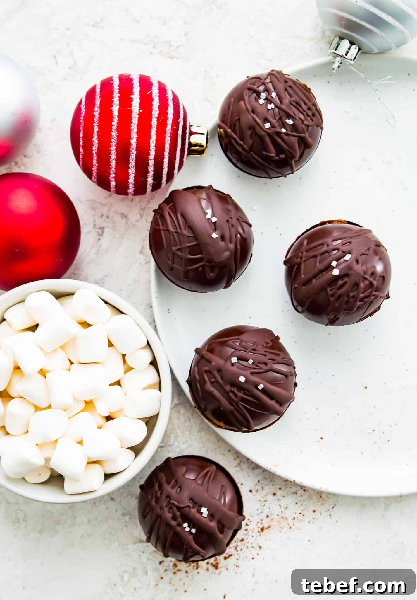 Vegan Hot Chocolate Recipe Dairy-free hot chocolate bombs on a plate with a bowl of marshmallows beside them.