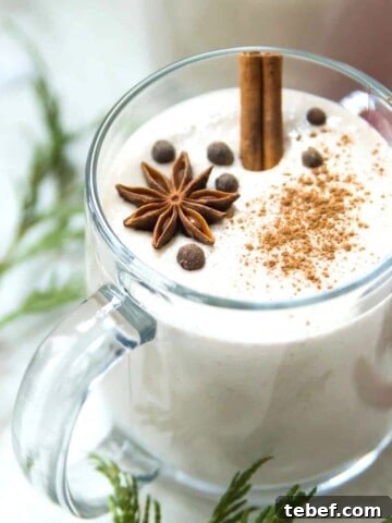 A mug of vegan eggnog garnished with star anise and ground cinnamon.