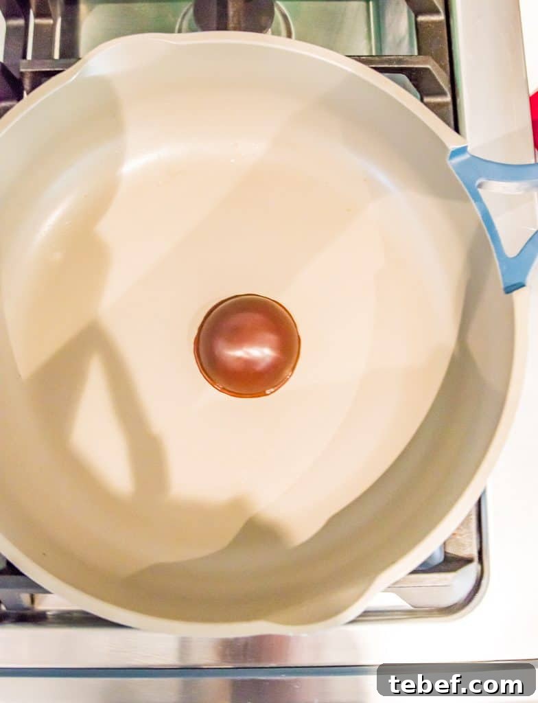 Vegan Hot Chocolate Bombs: Dairy-Free Paleo Recipe and How-To 7 Half a chocolate sphere being heated in a frying pan on the stovetop.