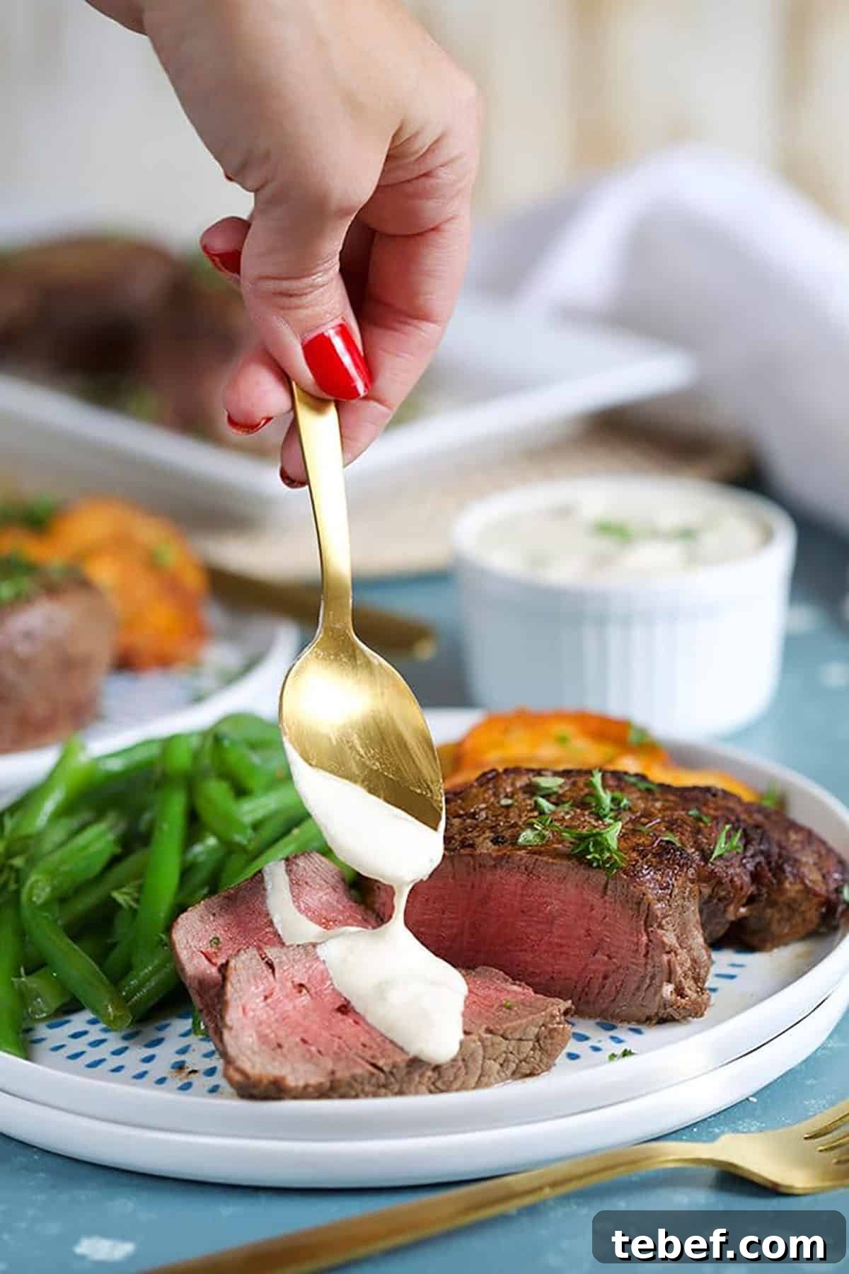 Creamy Horseradish Sauce Recipe: Smooth, Tangy & Versatile 2 Gold spoonful of horseradish sauce being spooned over beef tenderloin on a white plate.