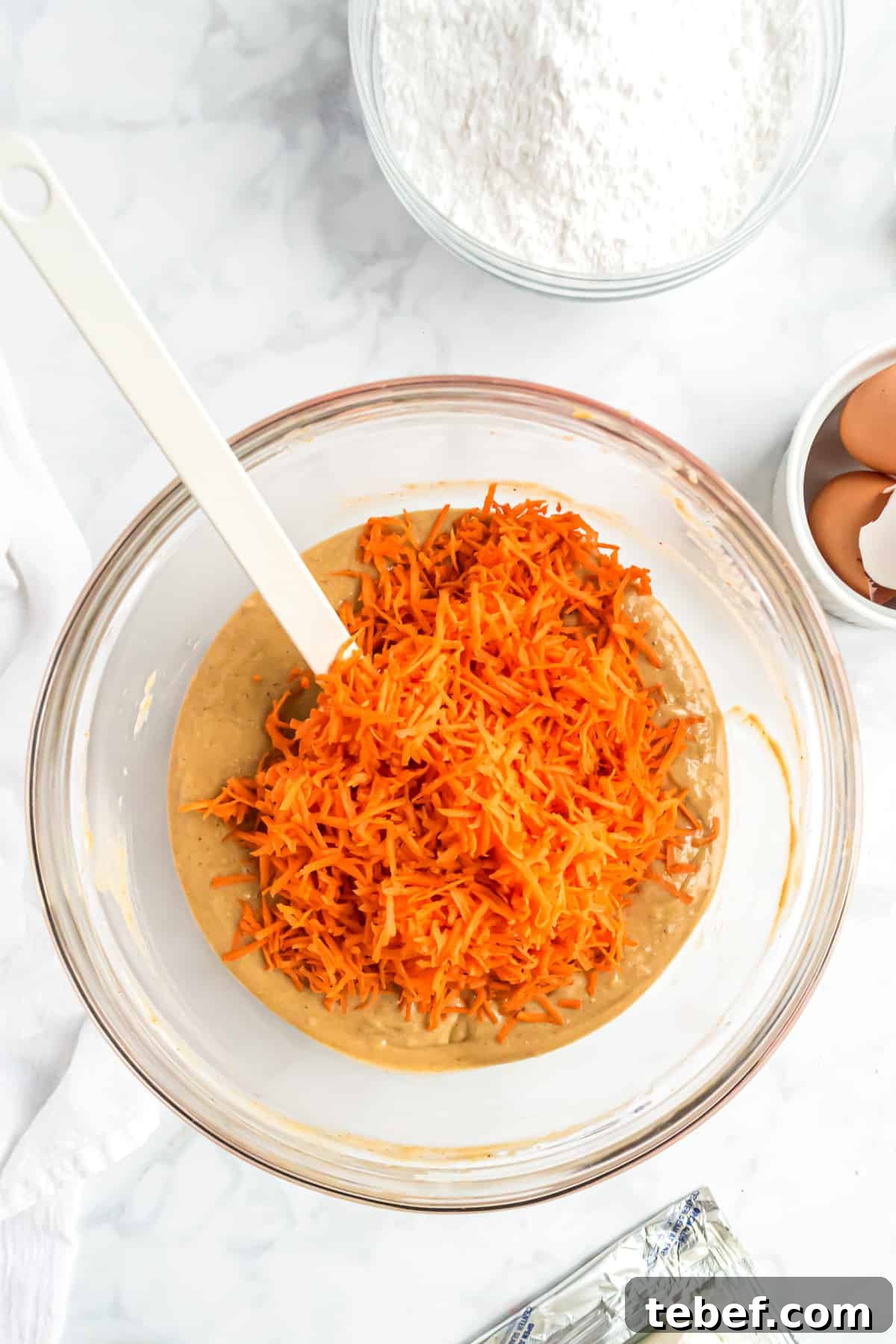 Shredded carrots added to a large bowl.