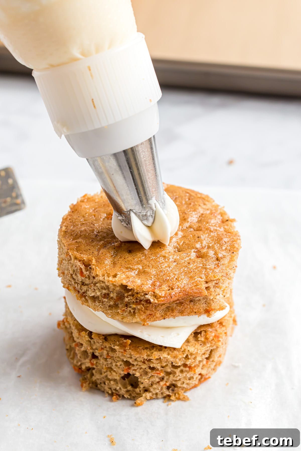 Second layer of cream cheese frosting being added to cake.