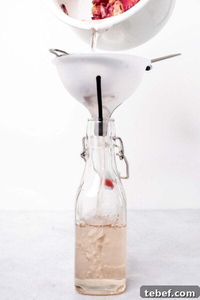 Homemade Rose Syrup Recipe for Fragrant Drinks and Desserts 5 Pouring rose syrup into a glass bottle.