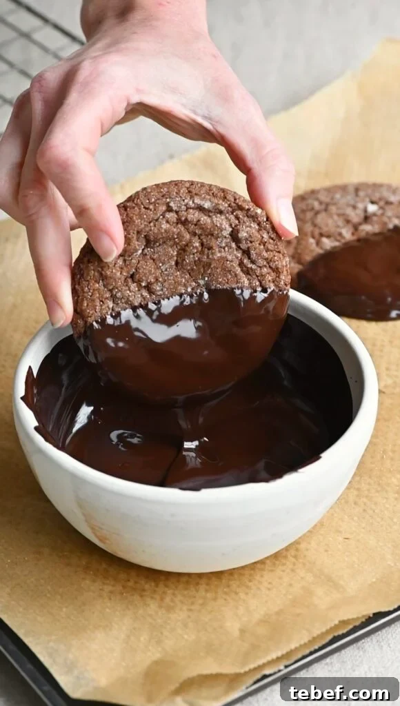 Chewy Chocolate Gingerbread Cookies Recipe for Holiday Baking 12 Hand dipping a cookie into a bowl of melted dark chocolate.