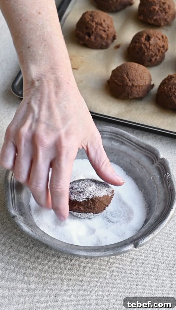 Chewy Chocolate Gingerbread Cookies Recipe for Holiday Baking 9 Hand rolling cookie dough balls in a bowl of sugar.