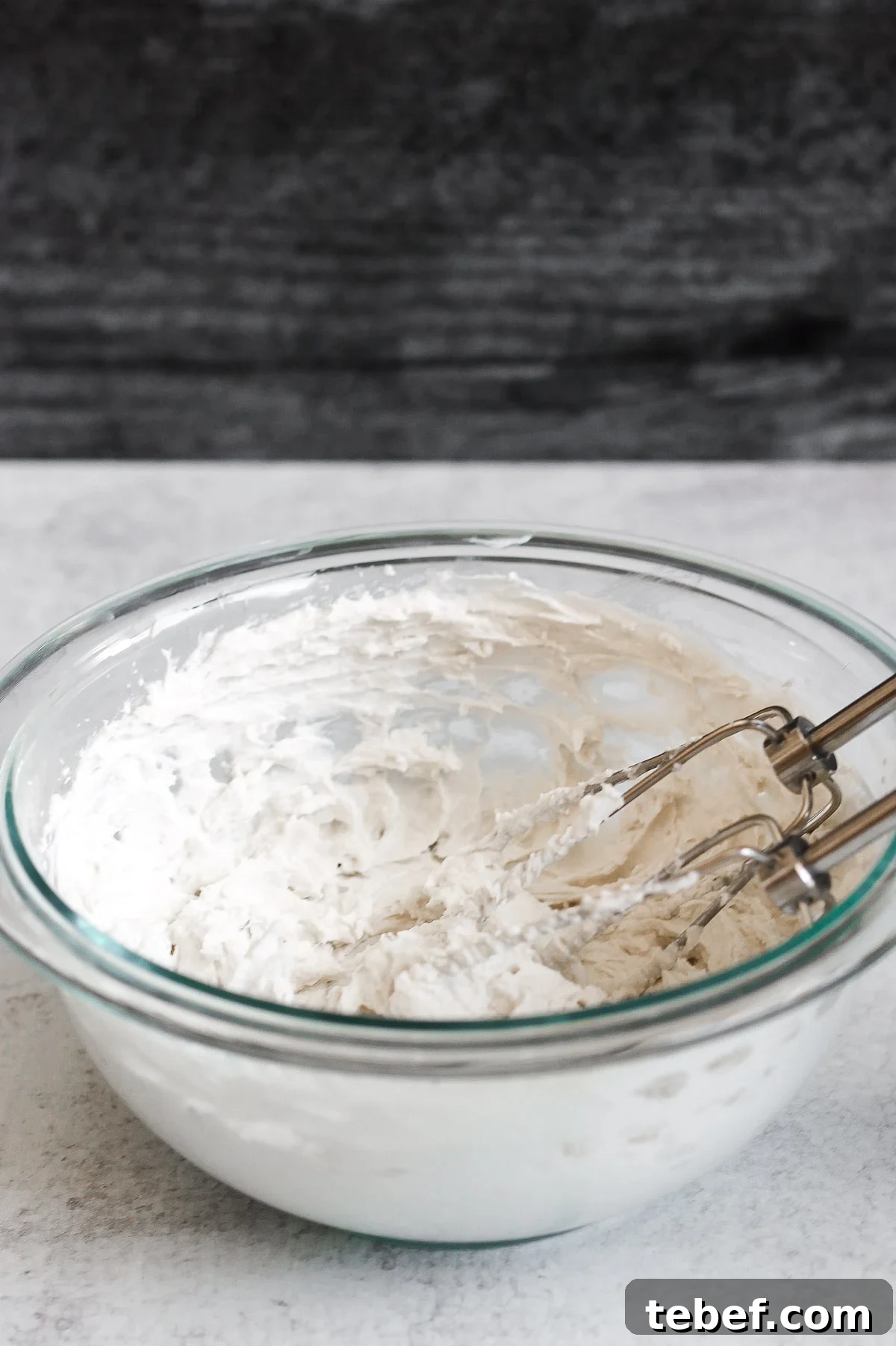 Coconut Whipped Cream Recipe: Light, Dairy-Free Topping in Minutes 5 side angle view of coconut whipped cream in glass mixing bowl with electric mixer whisks