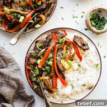 One-Pan Thai Basil Beef Stir-Fry Recipe 2 Thai basil beef on plates with green onions, cilantro, and rice