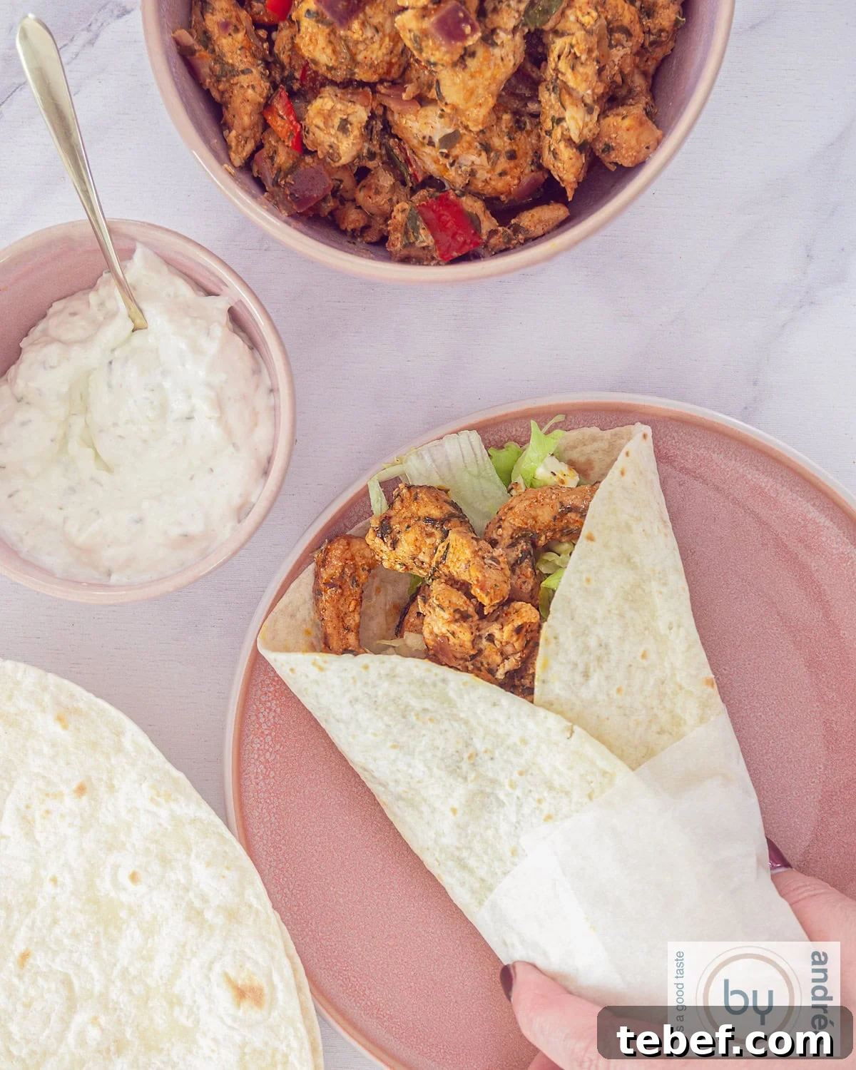 15-Minute Gyro Wraps with Fresh Tzatziki & Veggies 2 A photo from above with a wrap filled with gyros and raw vegetables. A container with sauce and a bowl with more gyros.