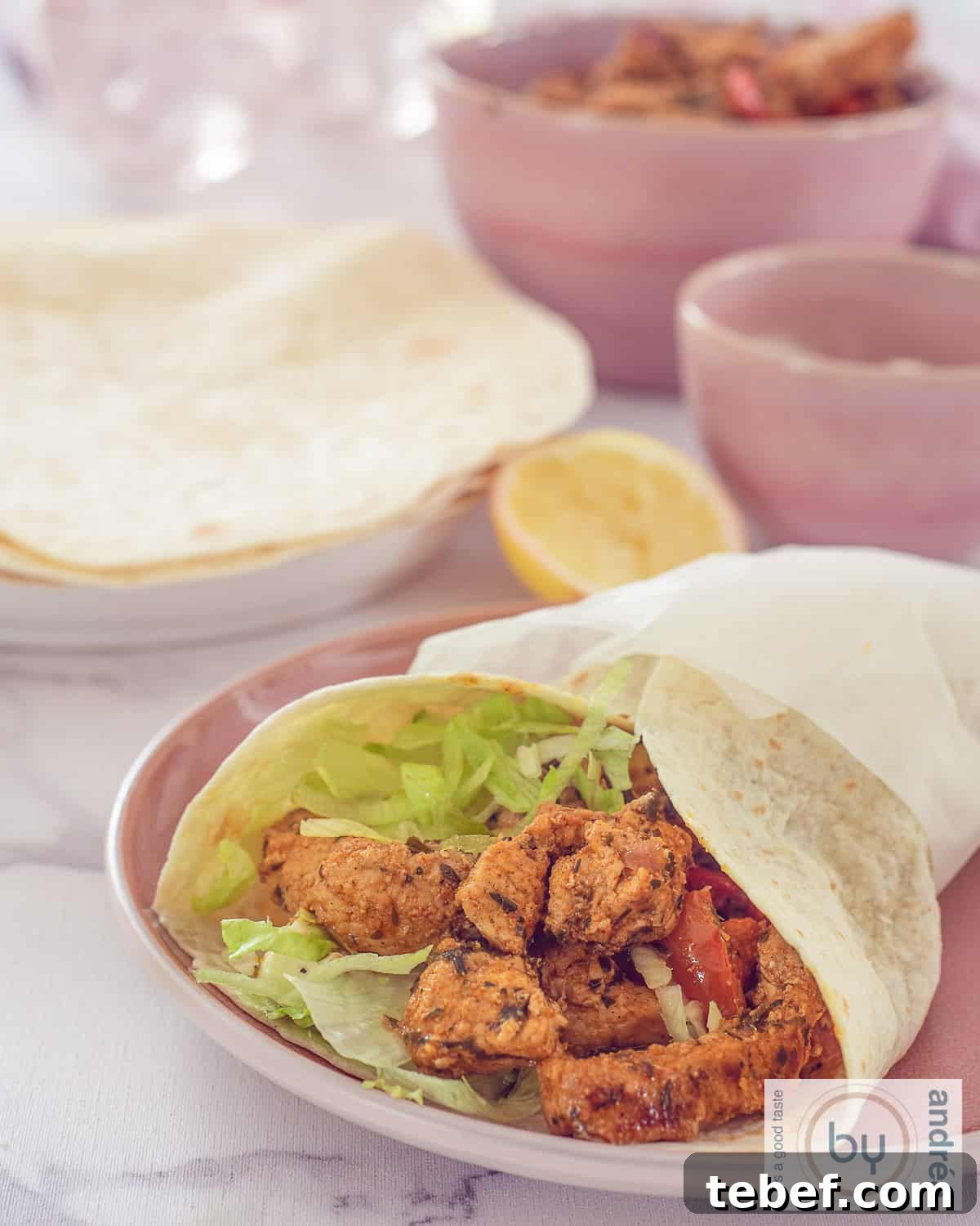 15-Minute Gyro Wraps with Fresh Tzatziki & Veggies 3 A height photo: a wrap filled with gyros meat and lettuce. In the background, wraps and bowls with side dishes.