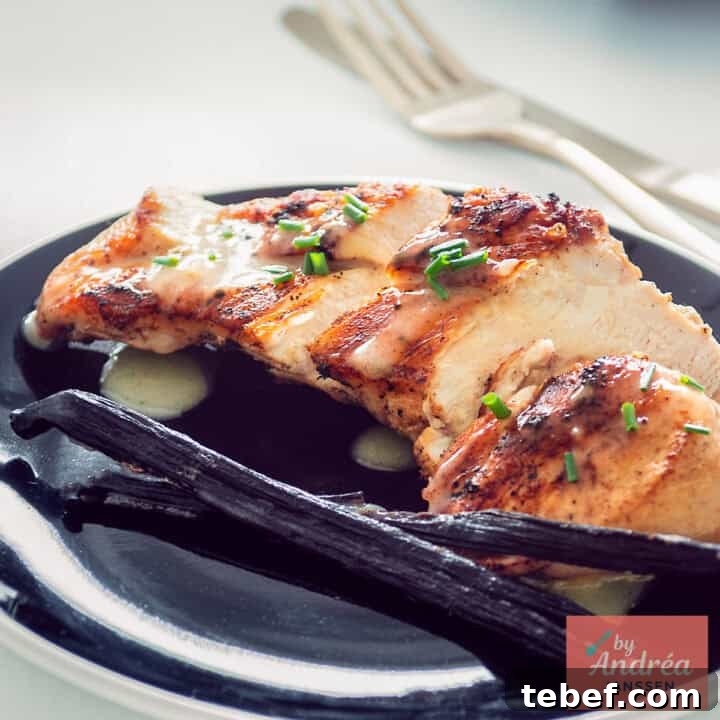 A square photo with chicken breast fried with vanilla sauce on a black plate.