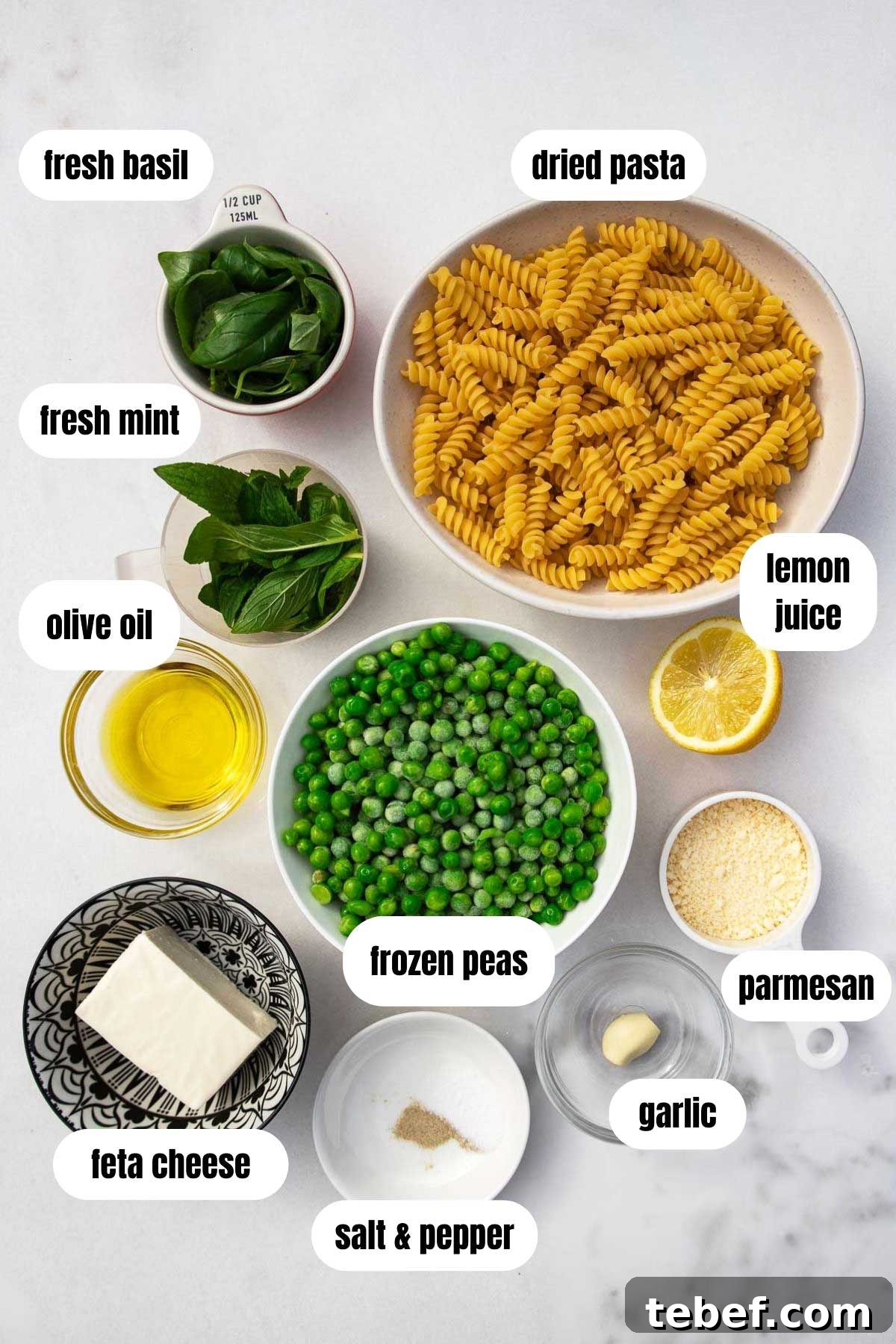 Creamy Green Pea Pasta with Frozen Peas — No Cream Needed 3 Overhead of all ingredients for a creamy pea pasta including fusilli pasta, feta, salt and pepper, frozen peas, garlic, parmesan, lemon juice parmesan, olive oil and fresh herbs, all on a marble background.