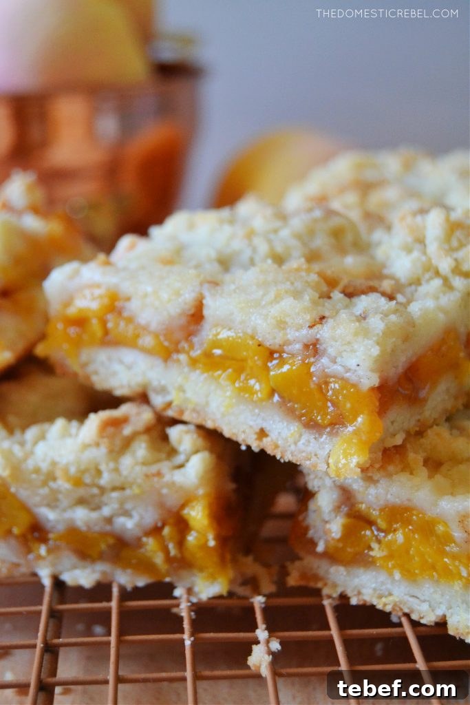 Peach Crumble Bars Recipe — Sweet Summer Dessert Bars 4 a closeup stack of peach crumble bars on a wire rack