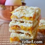 Peach Crumble Bars Recipe — Sweet Summer Dessert Bars 7 a trio'd stack of peach crumble bars on a rose gold wire rack