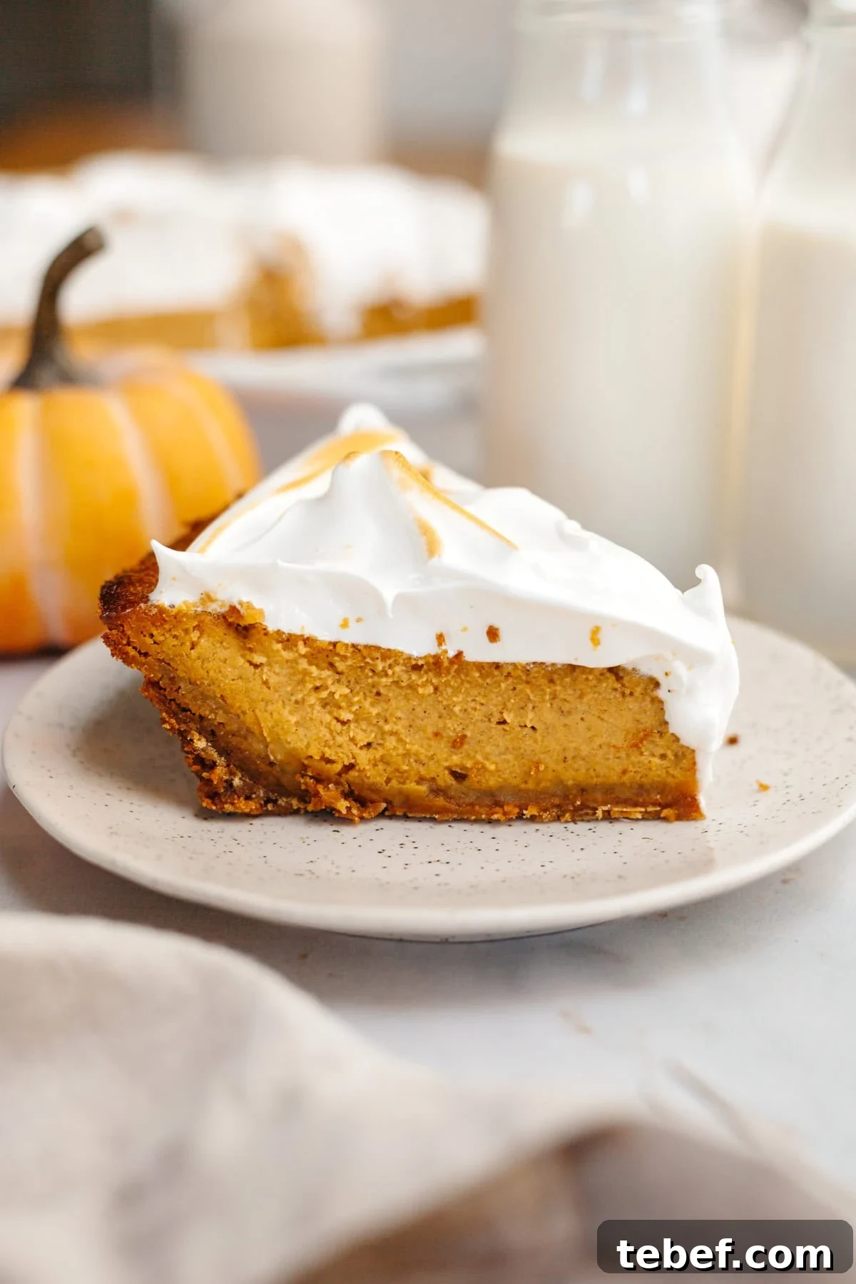 A slice of pumpkin pie with marshmallow topping on a small plate.