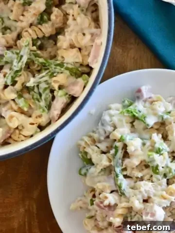 Creamy Ham and Asparagus Pasta in a white plate on a wooden tray