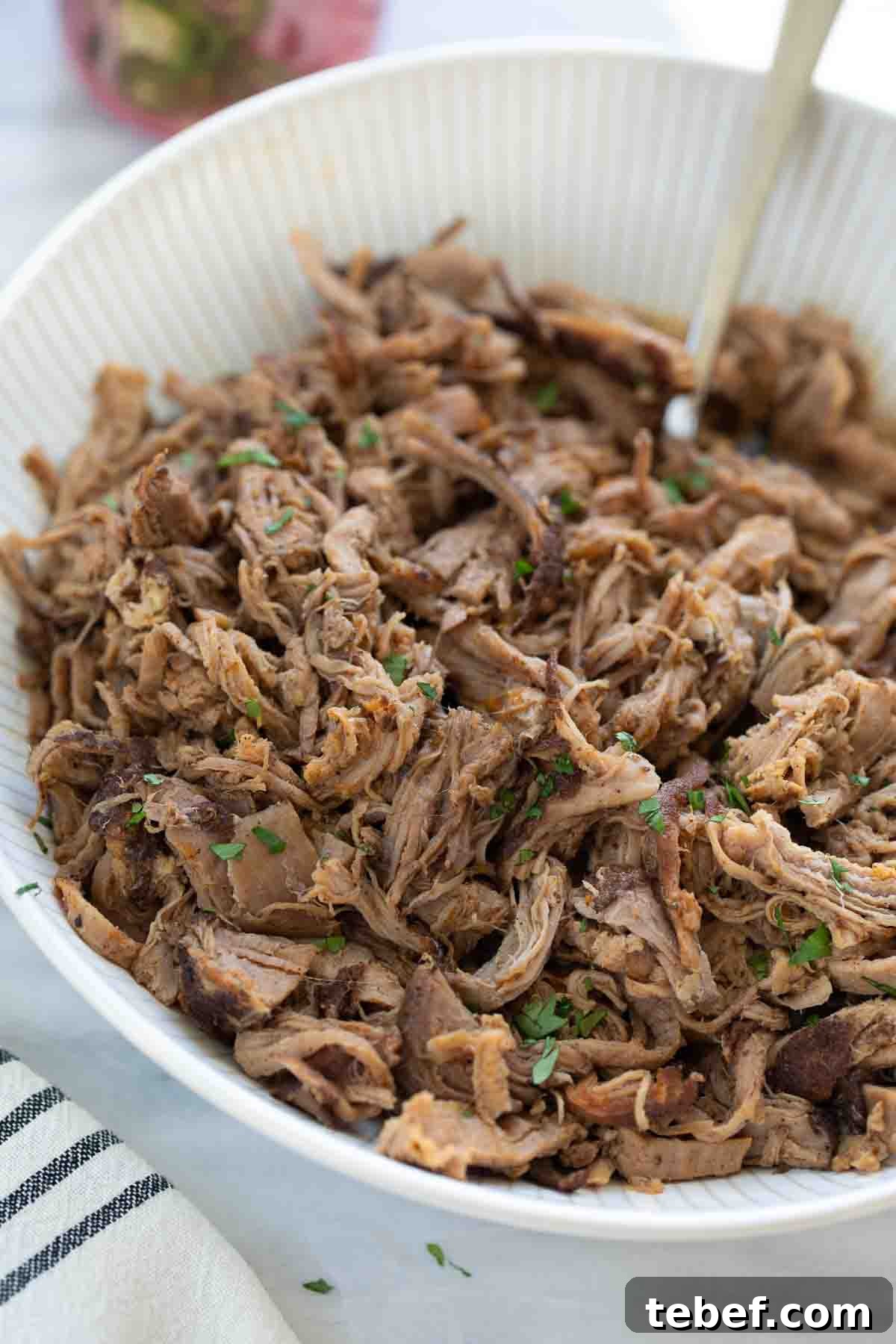 Slow-Cooker Sweet Pork Tacos Recipe for Tender, Flavorful Tacos 8 shredded pork tenderloin in white bowl topped with cilantro on marble background