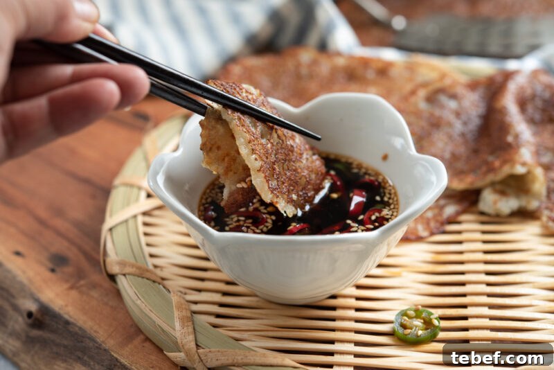 Crispy Korean Potato Pancakes (Gamja-Jeon) — Authentic Recipe 11 Chopsticks dipping crispy Korean potato pancake (gamja-jeon) into soy chili sauce