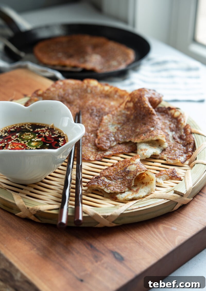 Crispy Korean Potato Pancakes (Gamja-Jeon) — Authentic Recipe 3 Thin Korean potato pancakes (gamja-jeon) served on a woven plate with soy chili dipping sauce