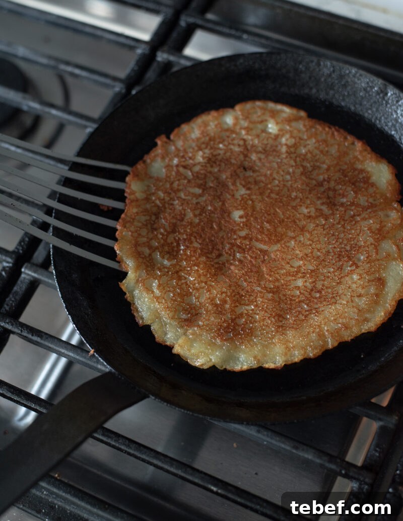 Crispy Korean Potato Pancakes (Gamja-Jeon) — Authentic Recipe 10 A spatula flipping Korean potato pancake (gamja-jeon) to reveal its golden, crispy side