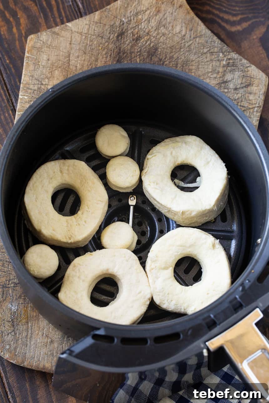 Uncooked doughnuts in air fryer basket.