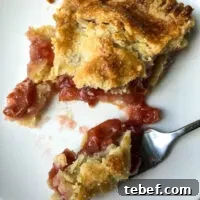 Classic Homemade Cherry Pie Recipe with Flaky Crust 9 Piece of pie on white plate with forkful.