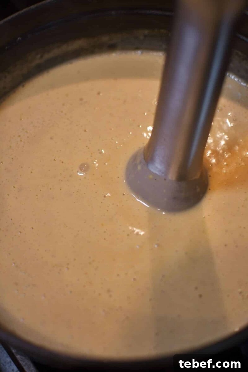 Creamy Beer Cheese Soup Recipe with Bacon and Pretzel Croutons 11 Blending the cheese into the soup to make it smooth.