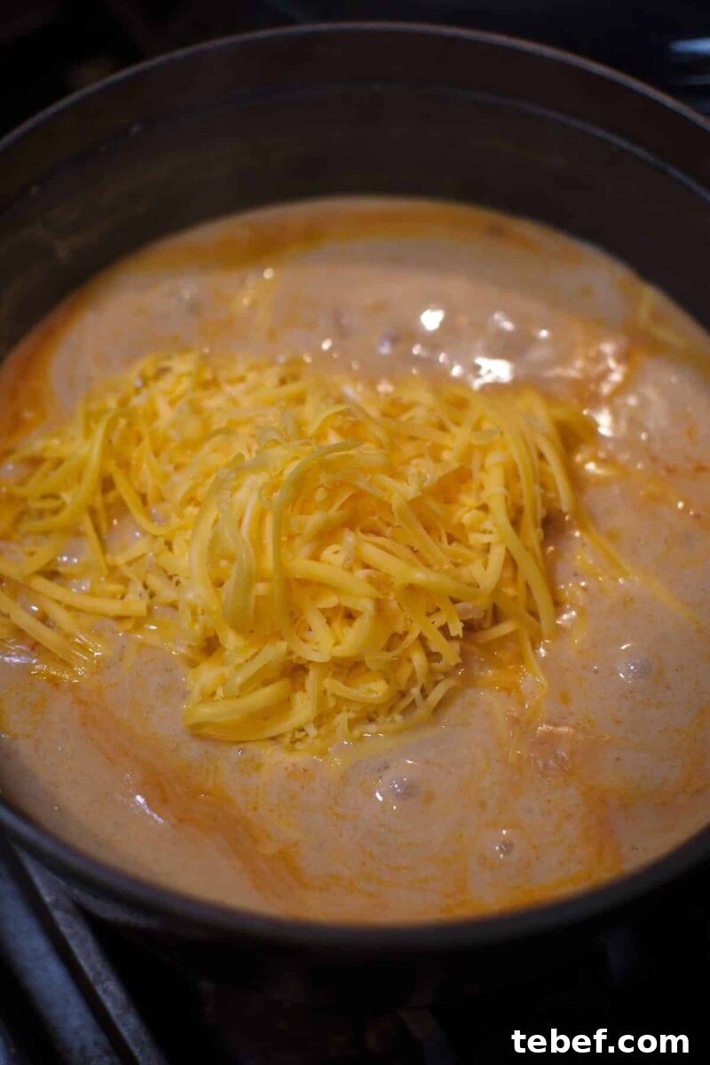 Creamy Beer Cheese Soup Recipe with Bacon and Pretzel Croutons 10 Adding the cheese to the soup before blending to make it smooth.