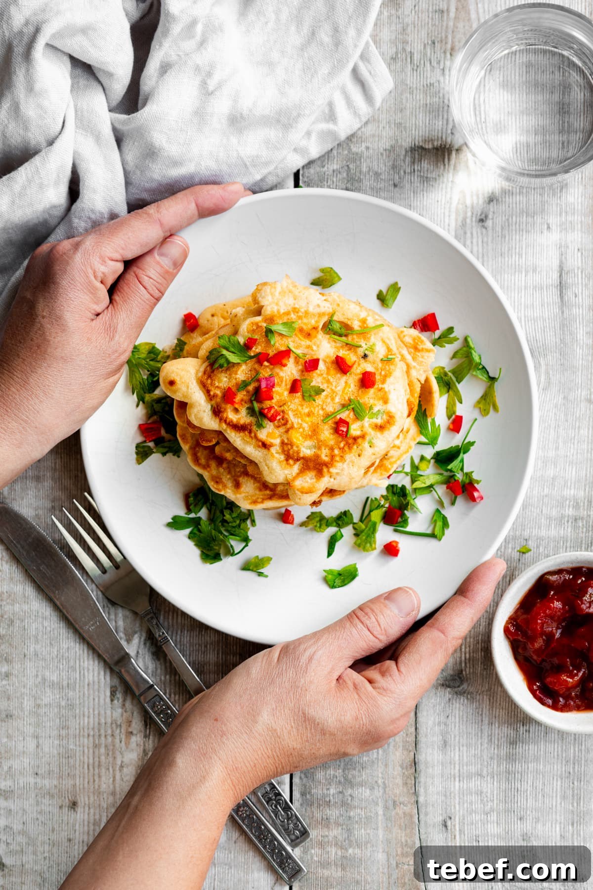 Crispy Sweetcorn and Spring Onion Fritters Recipe 5 Hands putting down a plate of sweetcorn fritters
