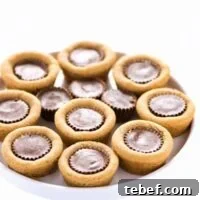 Gluten Free Reese’s Peanut Butter Cookie Cups are a chocolate + peanut butter lovers’ dream cookie! They’re peanut butter cookies baked in mini muffin tins then stuffed with peanut butter cups. Simply amazing! SUPER EASY cookie recipe to make too! Recipe from @whattheforkblog | whattheforkfoodblog.com | gluten free cookie recipes | easy dessert recipes | homemade peanut butter cookies | how to make peanut butter cookies | #glutenfree #chocolate #peanutbutter #cookies #dessert #easyrecipes