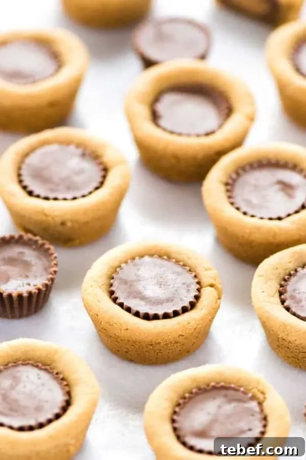 Gluten Free Reese’s Peanut Butter Cookie Cups are a chocolate + peanut butter lovers’ dream cookie! They’re peanut butter cookies baked in mini muffin tins then stuffed with peanut butter cups. Simply amazing! SUPER EASY cookie recipe to make too! Recipe from @whattheforkblog | whattheforkfoodblog.com | gluten free cookie recipes | easy dessert recipes | homemade peanut butter cookies | how to make peanut butter cookies | #glutenfree #chocolate #peanutbutter #cookies #dessert #easyrecipes