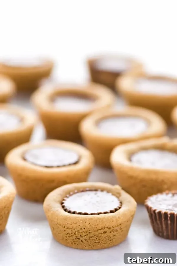 Gluten Free Reese’s Peanut Butter Cookie Cups are a chocolate + peanut butter lovers’ dream cookie! They’re peanut butter cookies baked in mini muffin tins then stuffed with peanut butter cups. Simply amazing! SUPER EASY cookie recipe to make too! Recipe from @whattheforkblog | whattheforkfoodblog.com | gluten free cookie recipes | easy dessert recipes | homemade peanut butter cookies | how to make peanut butter cookies | #glutenfree #chocolate #peanutbutter #cookies #dessert #easyrecipes