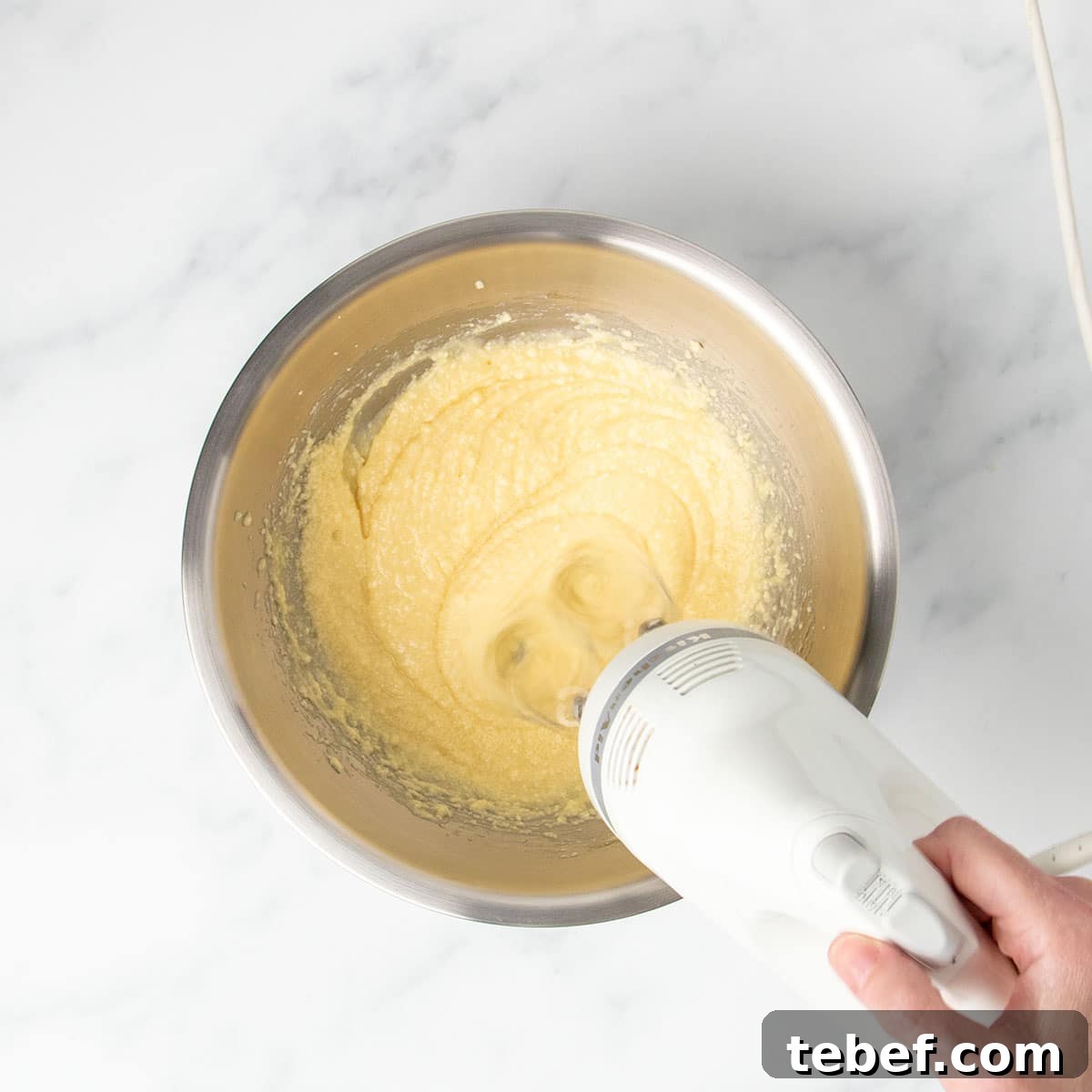 Gluten-Free Vanilla Cupcakes Recipe for Moist, Fluffy Results 8 white handheld mixer beating light yellow mixture in same mixing bowl