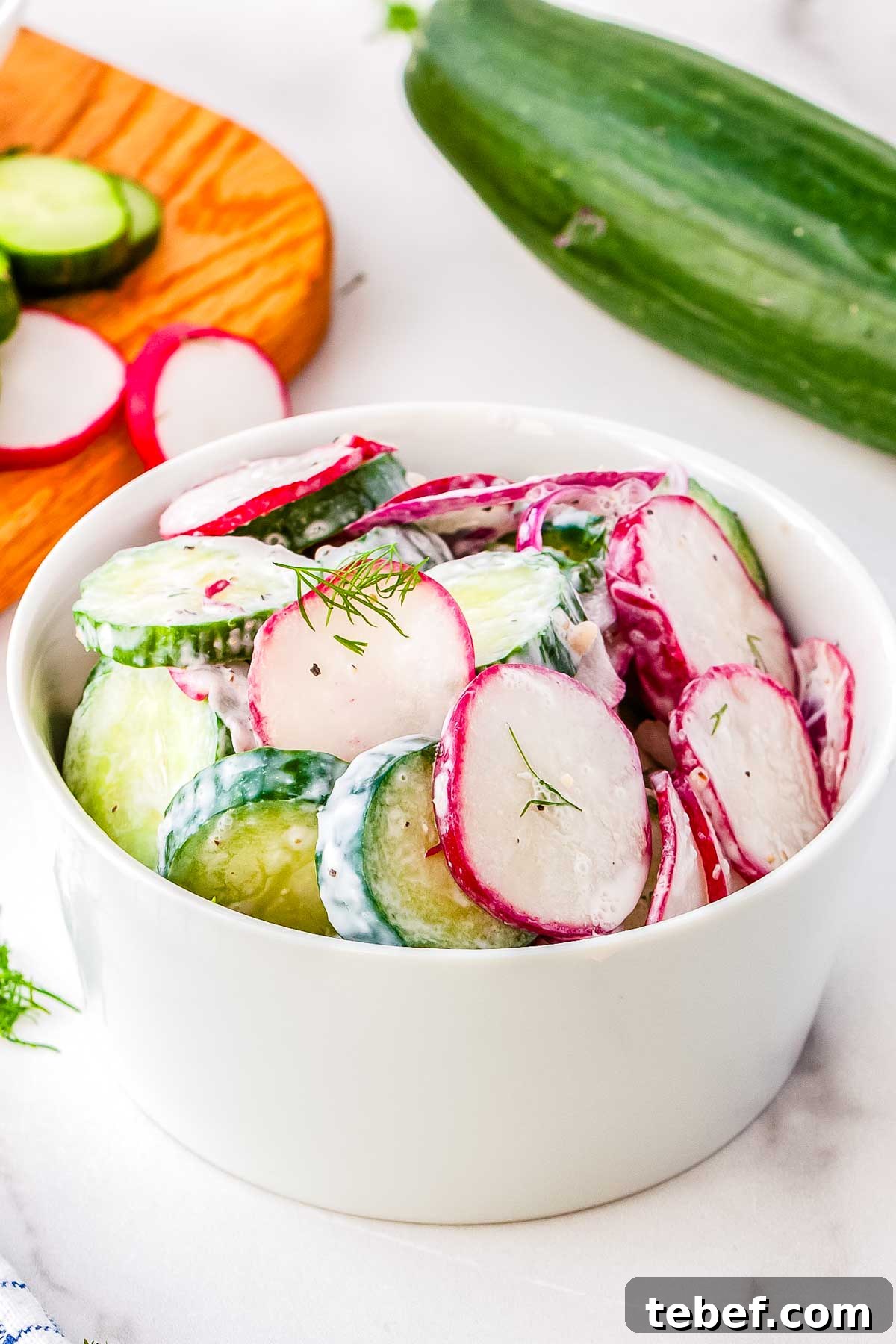 A bowl of cucumber and radish salad garnished with fresh dill.
