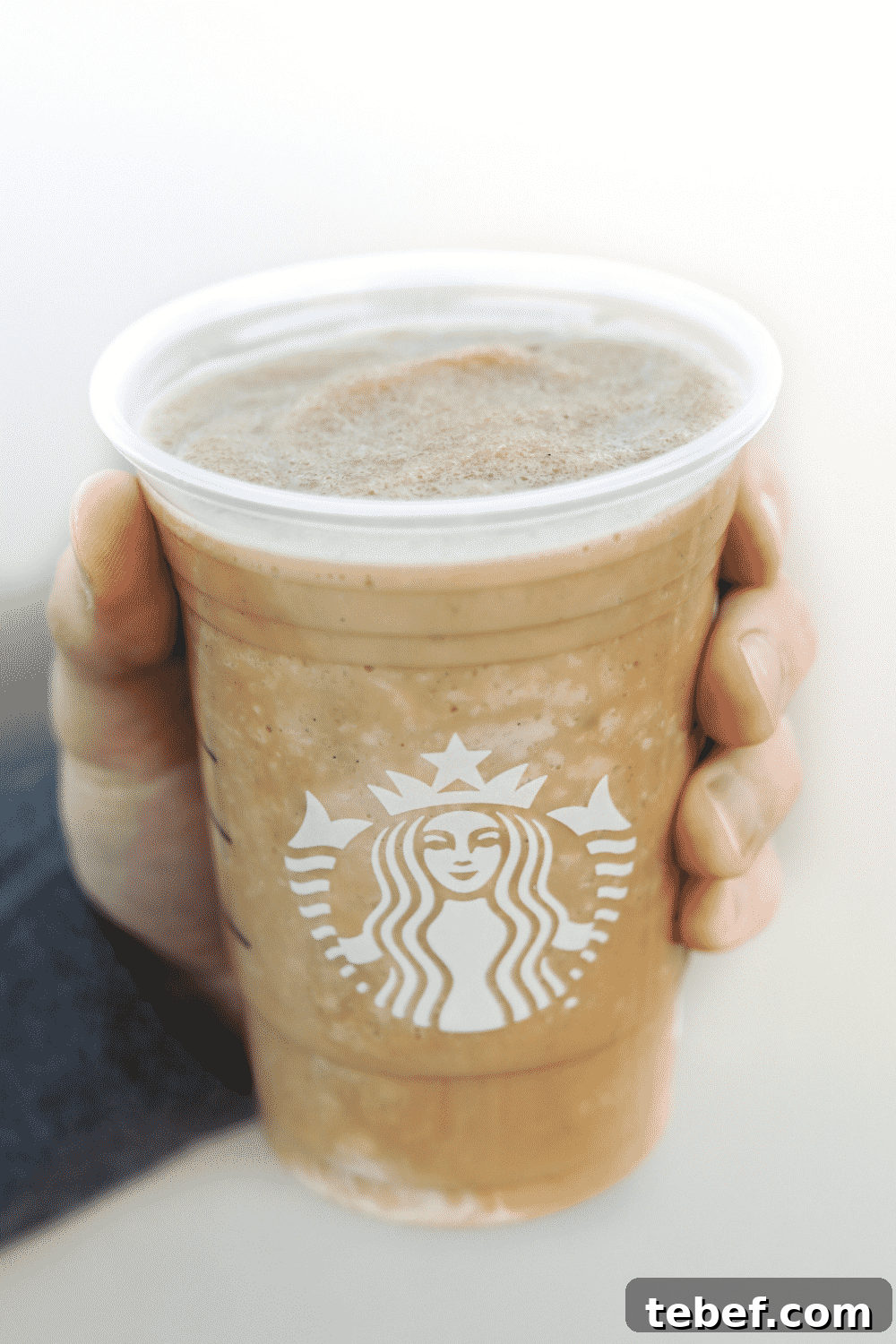 A hand holding a cup of Starbucks vegan caffe vanilla Frappuccino
