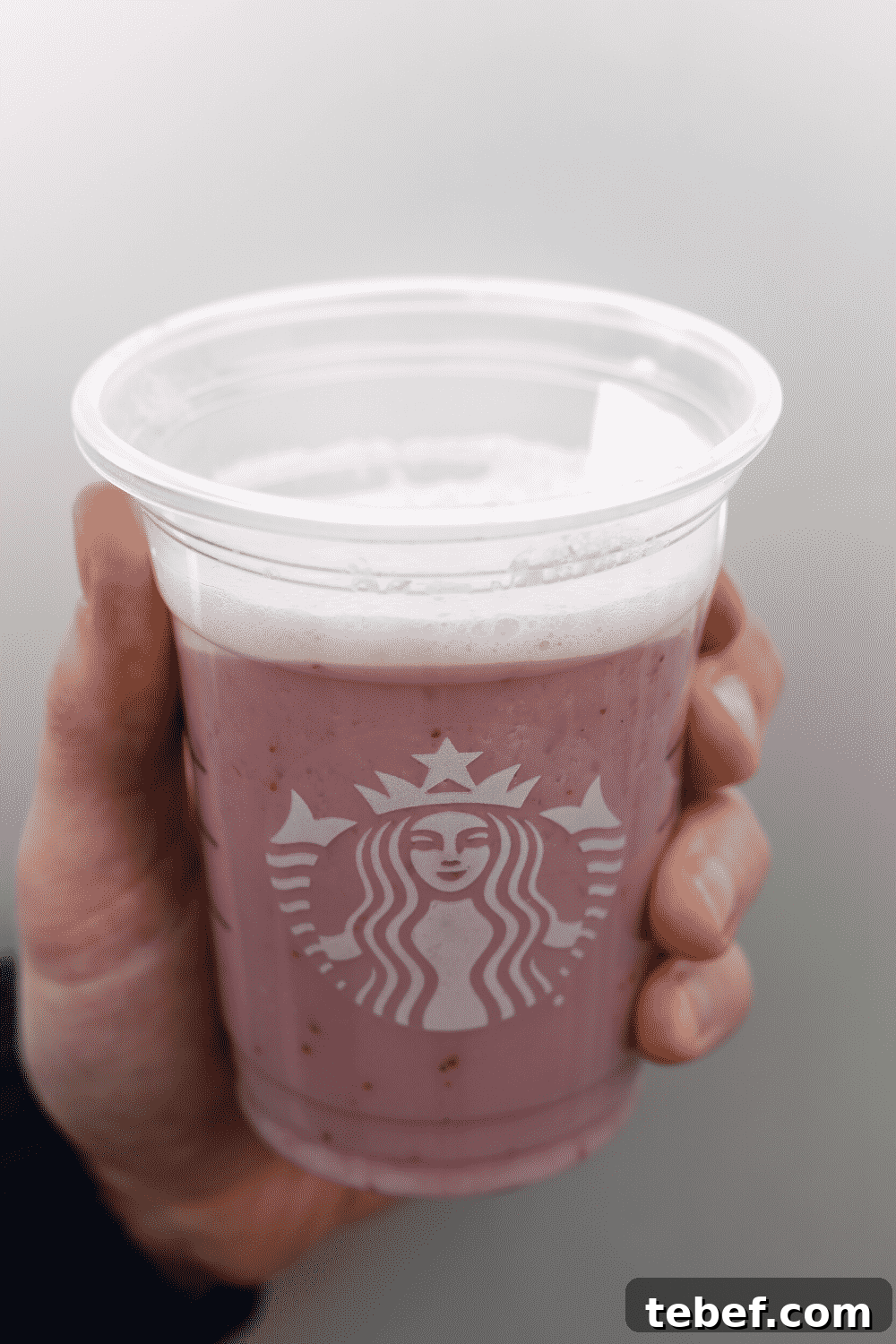 A hand holding a cup of Starbucks vegan strawberry creme Frappuccino