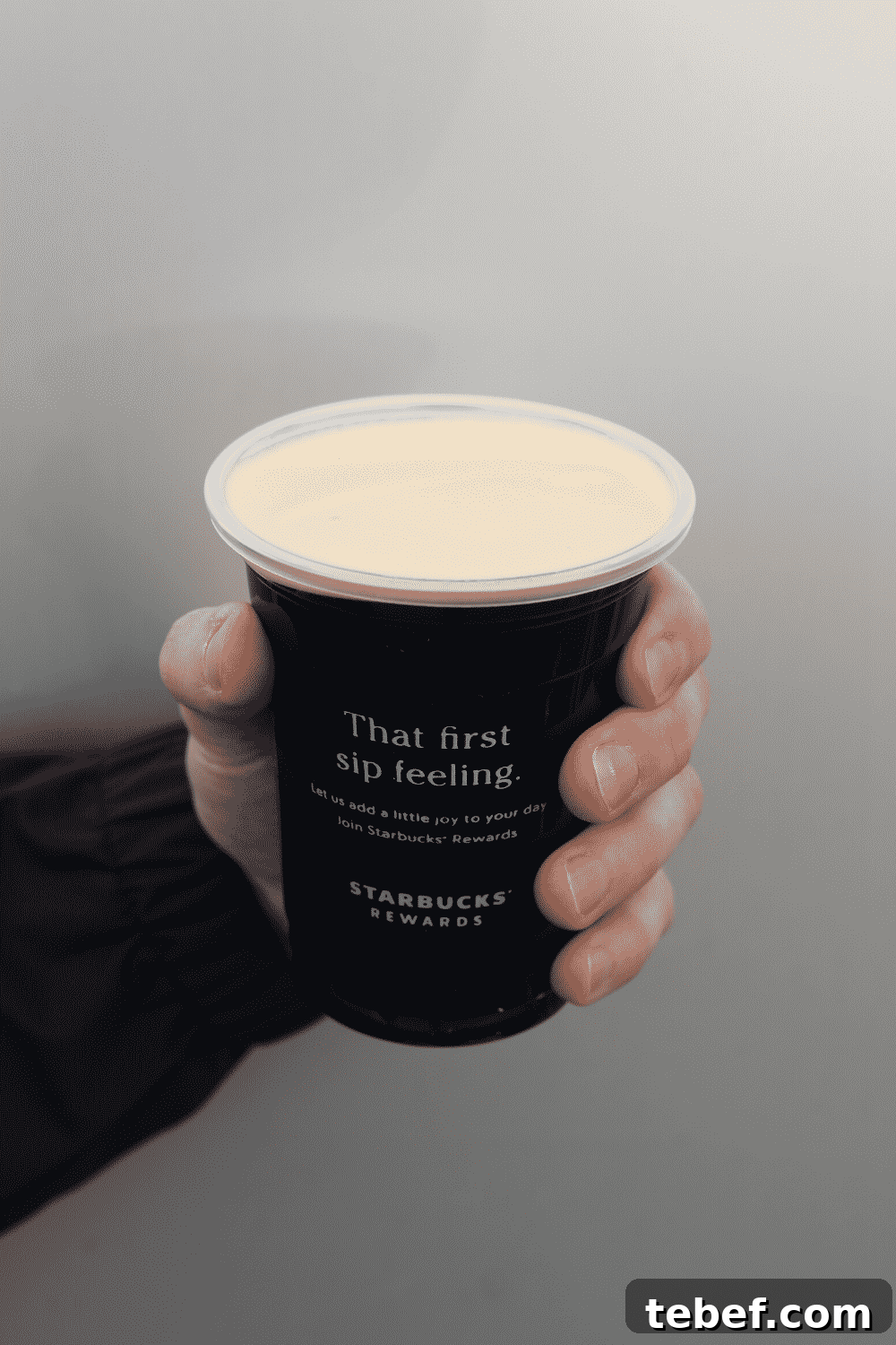 A hand holding a cup of Starbucks vegan nitro cold brew.