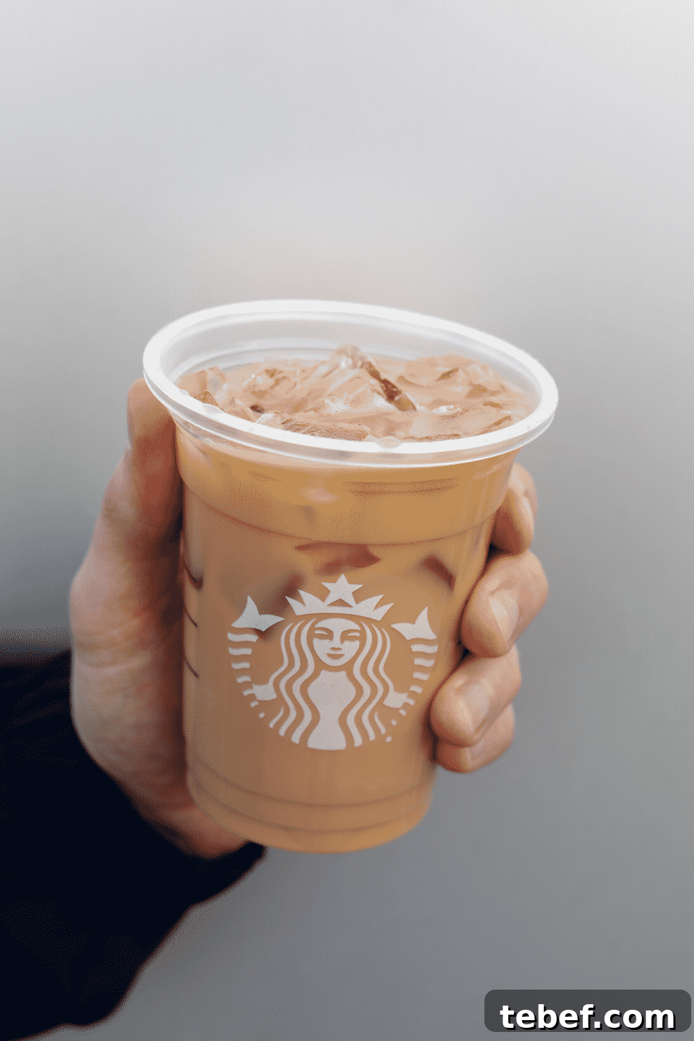 A hand holding a cup of Starbucks vegan iced coffee.