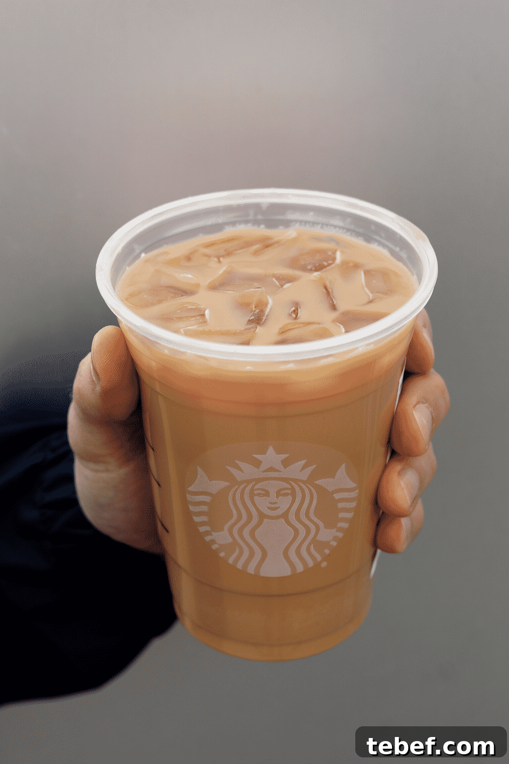 A hand holding a cup of Starbucks vegan iced Caffe latte