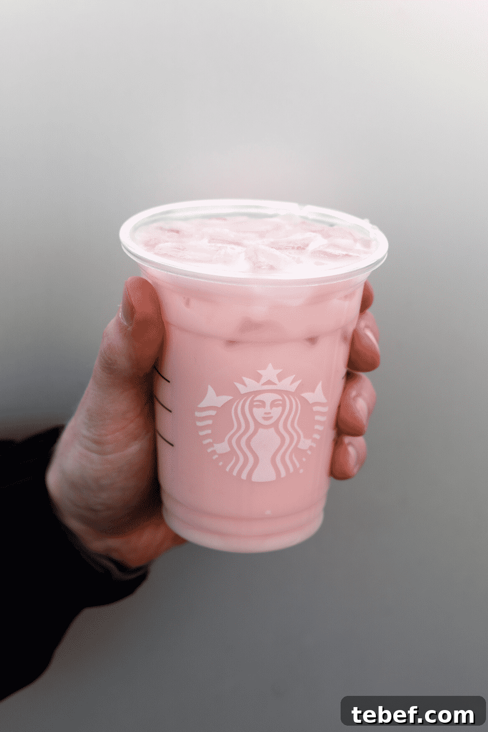A hand holding Starbucks vegan iced guava passionfruit.